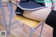 A woman in a school uniform is sitting on a chair.