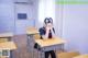 A woman sitting at a desk in a classroom.