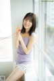 A woman sitting on a window sill holding a red string.