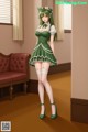 A woman in a green dress and white stockings standing in a room.