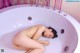 A naked woman laying in a bathtub in a bathroom.