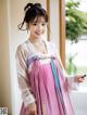 A woman in a pink and blue hanbok is posing for a picture.