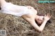 A woman laying on top of a pile of hay.