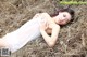 A woman laying on a pile of hay in a white dress.