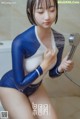 A woman in a blue and white bodysuit is taking a shower.