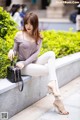 A woman sitting on a ledge with a handbag.