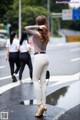 A woman standing in the middle of a street with her back to the camera.