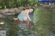 A woman in a blue and white striped bikini is standing in the water.