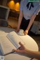 A waitress is holding a cup of coffee and a book.