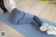 A woman in a gray sports bra top and gray leggings is doing a yoga pose.