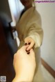 A woman in a beige jacket is putting a ring on a man's finger.