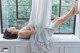 A woman laying on a window sill with her legs up.