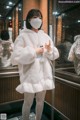 A woman wearing a white coat and a face mask.