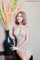 A woman sitting next to a vase of flowers on a table.