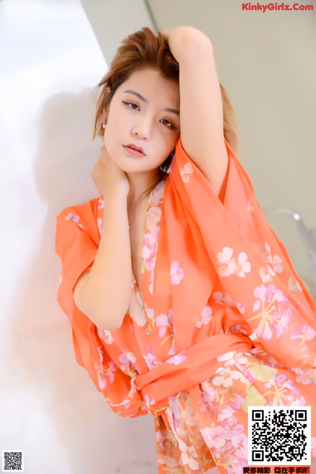A woman in an orange kimono posing for a picture.
