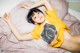 A woman laying on top of a bed wearing a yellow shirt.