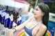 A woman in a bikini standing next to a pool with bottles of beer.