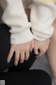 A close up of a person's hands with a white sweater.