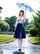 A woman in a school uniform holding an umbrella.