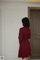 A woman standing in front of a door wearing a red dress.