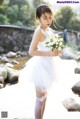 A woman in a white dress holding a bouquet of flowers.