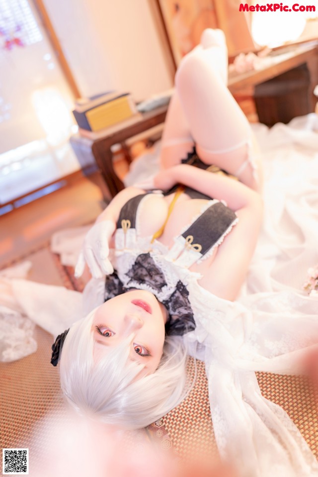 A woman in a maid outfit laying on a bed.