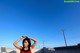 A woman standing on top of a roof with her hands behind her head.