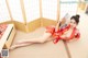 A woman in a red kimono laying on the floor holding a fan.