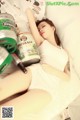 A woman laying on a bed next to a can of beer.