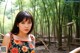 A woman in a floral dress standing in front of a bamboo forest.