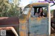 A woman sitting in the driver's seat of an old truck.