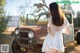 A woman in a white dress standing next to an old truck.