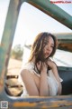 A woman in a white dress leaning against an old truck.